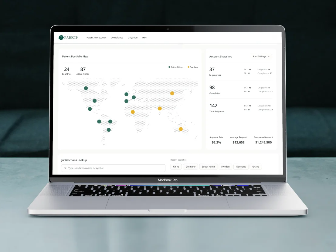 MacBook Pro on a desk displaying the legal studio dashboard with a world map of patent filings, account metrics, and portfolio statistics in a clean, light-themed interface.