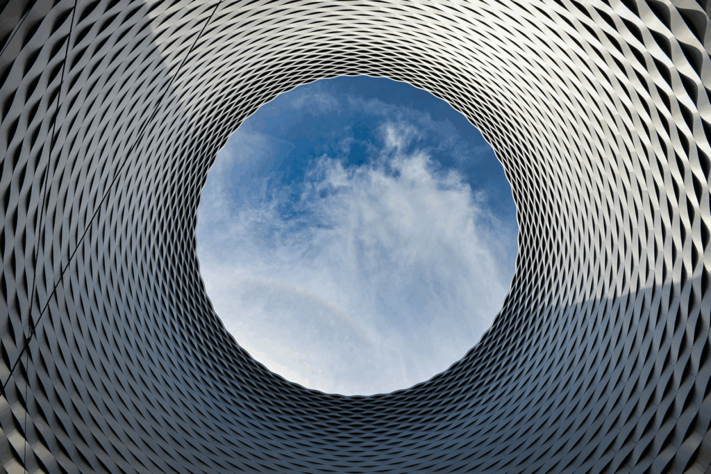 Circular architectural structure with geometric pattern and open sky at the center